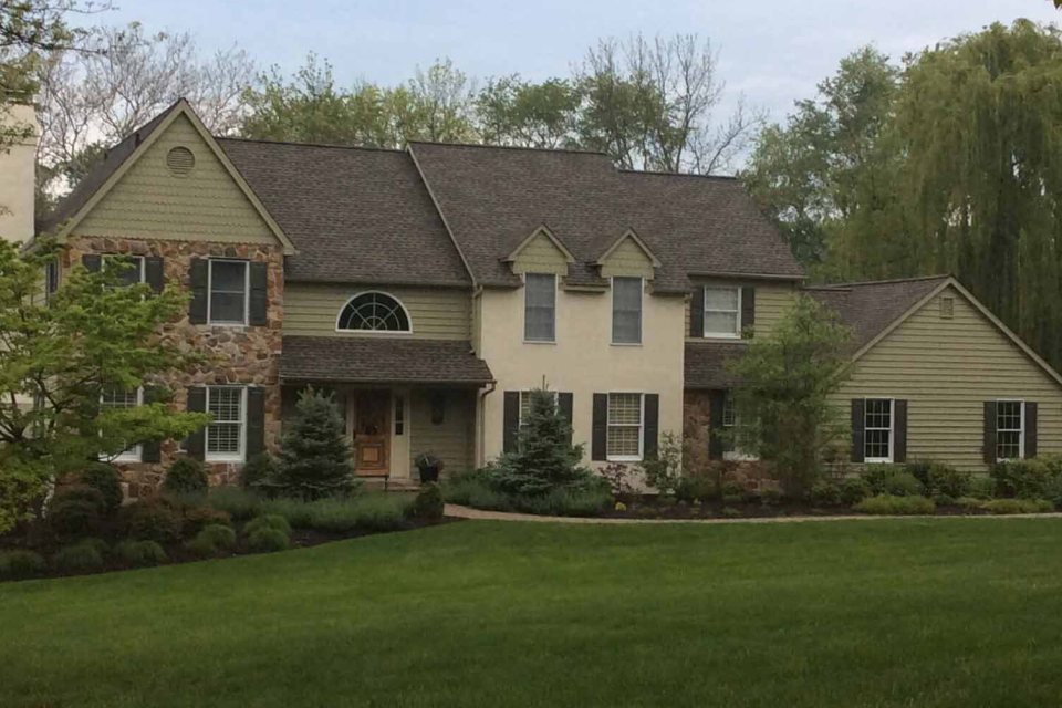 Shingle roof on a stone-and-siding colonial with an arched window